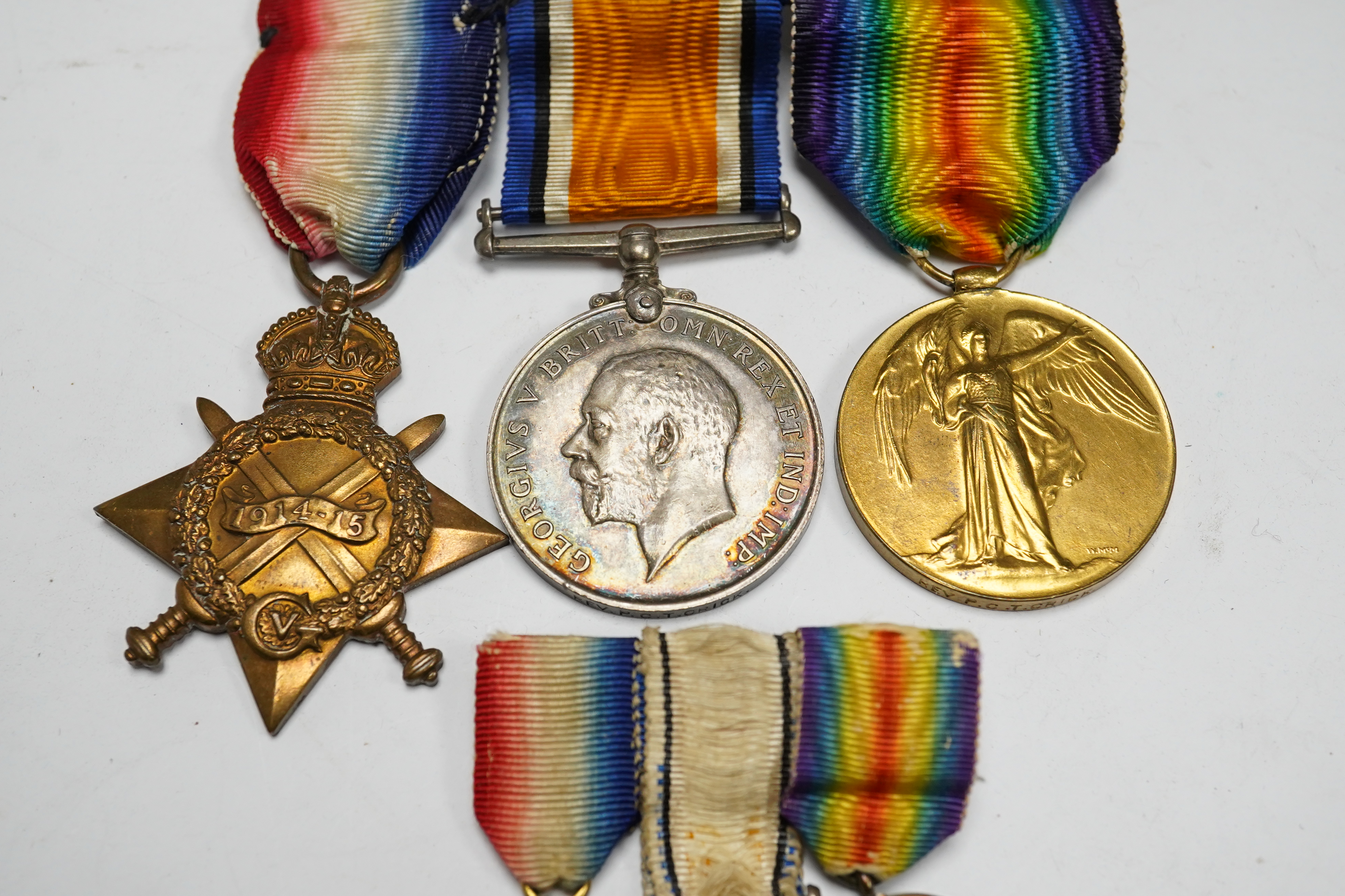 A First World War medal trio awarded to the Rev. P.C.T. Crick A.C.D., together with the miniature set. Condition - poor to fair.